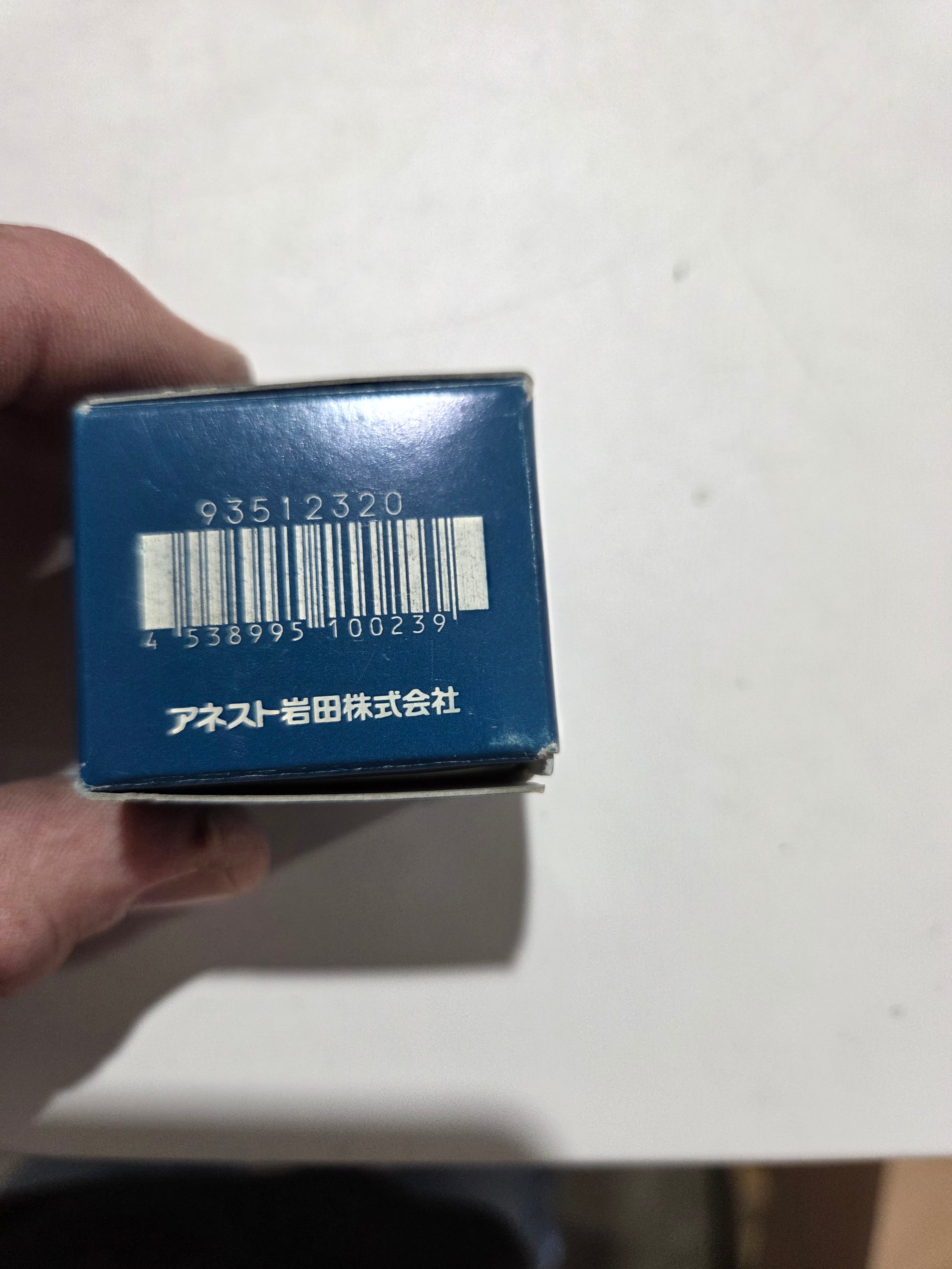 Hand holding a blue box with a barcode on a white background