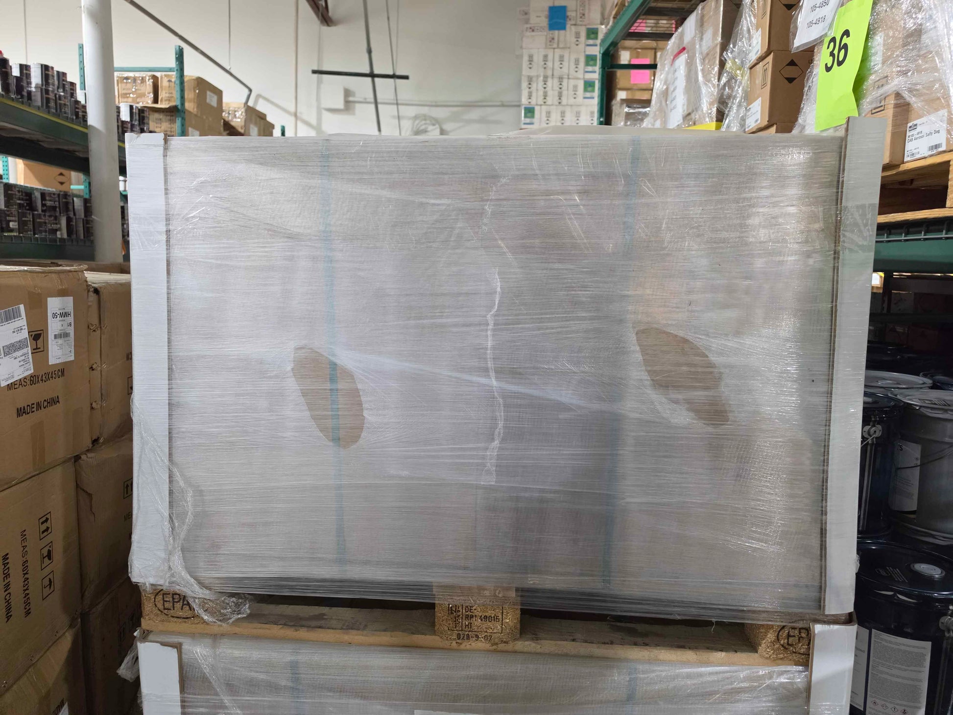 Large metal panel wrapped in plastic on a pallet in a warehouse setting