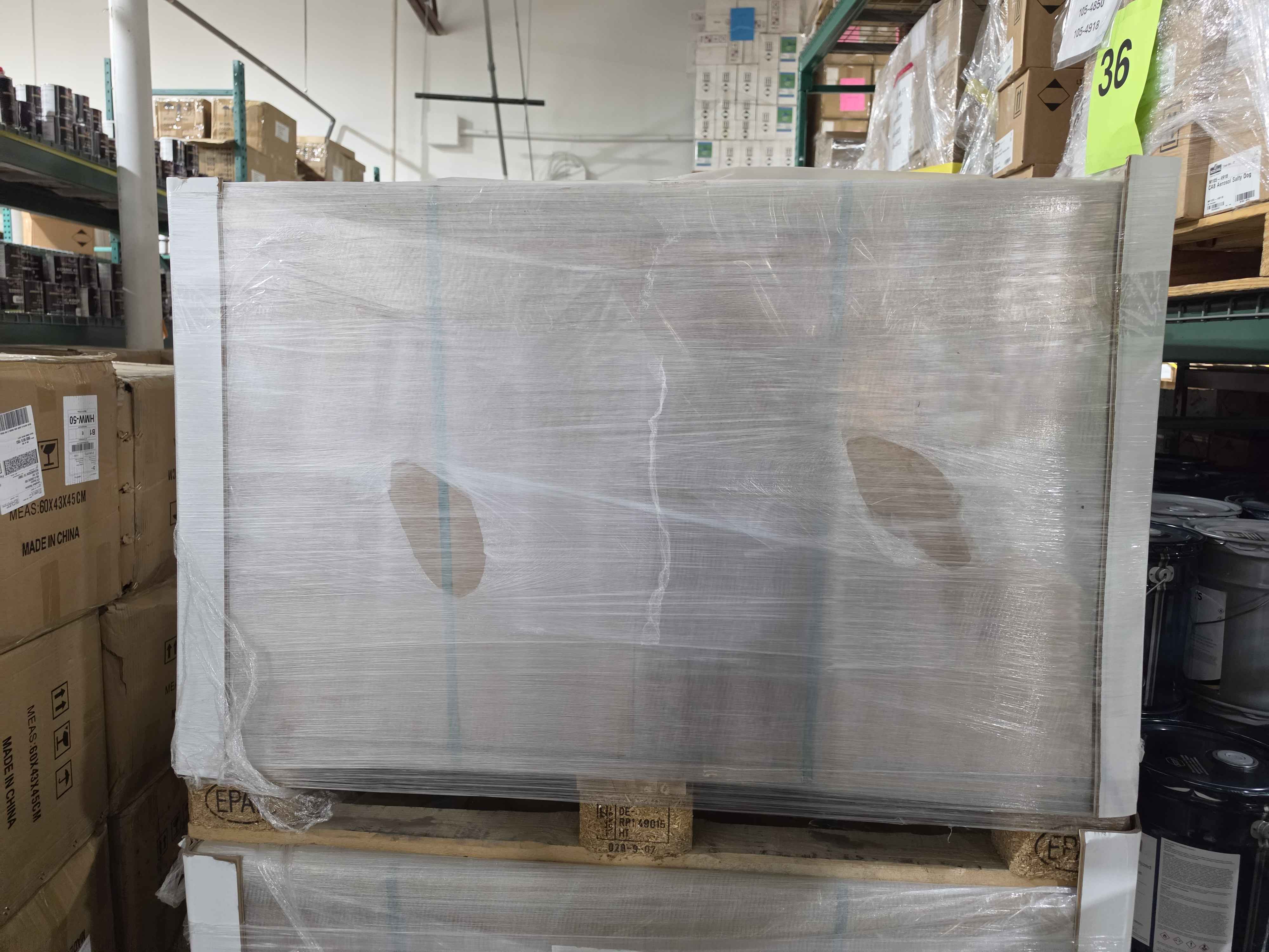 Large metal panel wrapped in plastic on a pallet in a warehouse setting