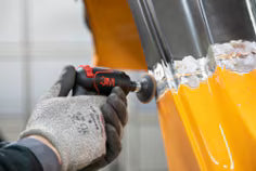 Person using a tool on a yellow object with a white background