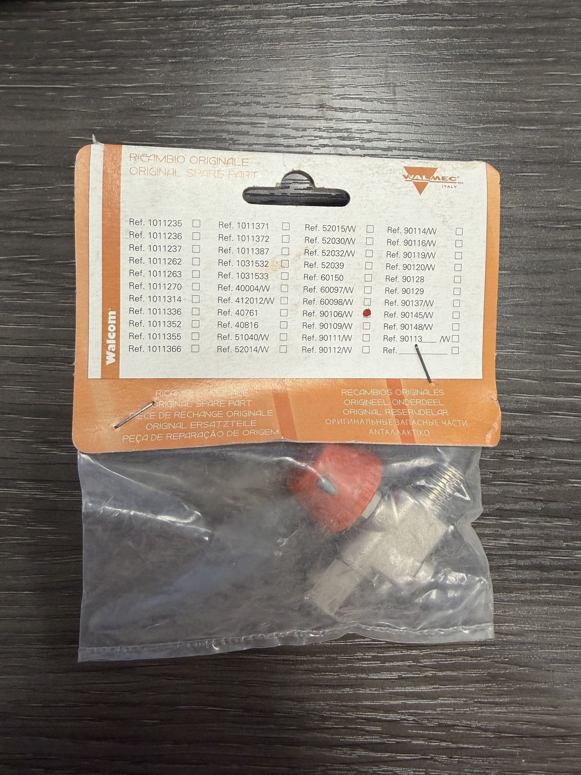 Small electronic component in a clear plastic bag on an orange label with text and checkboxes.