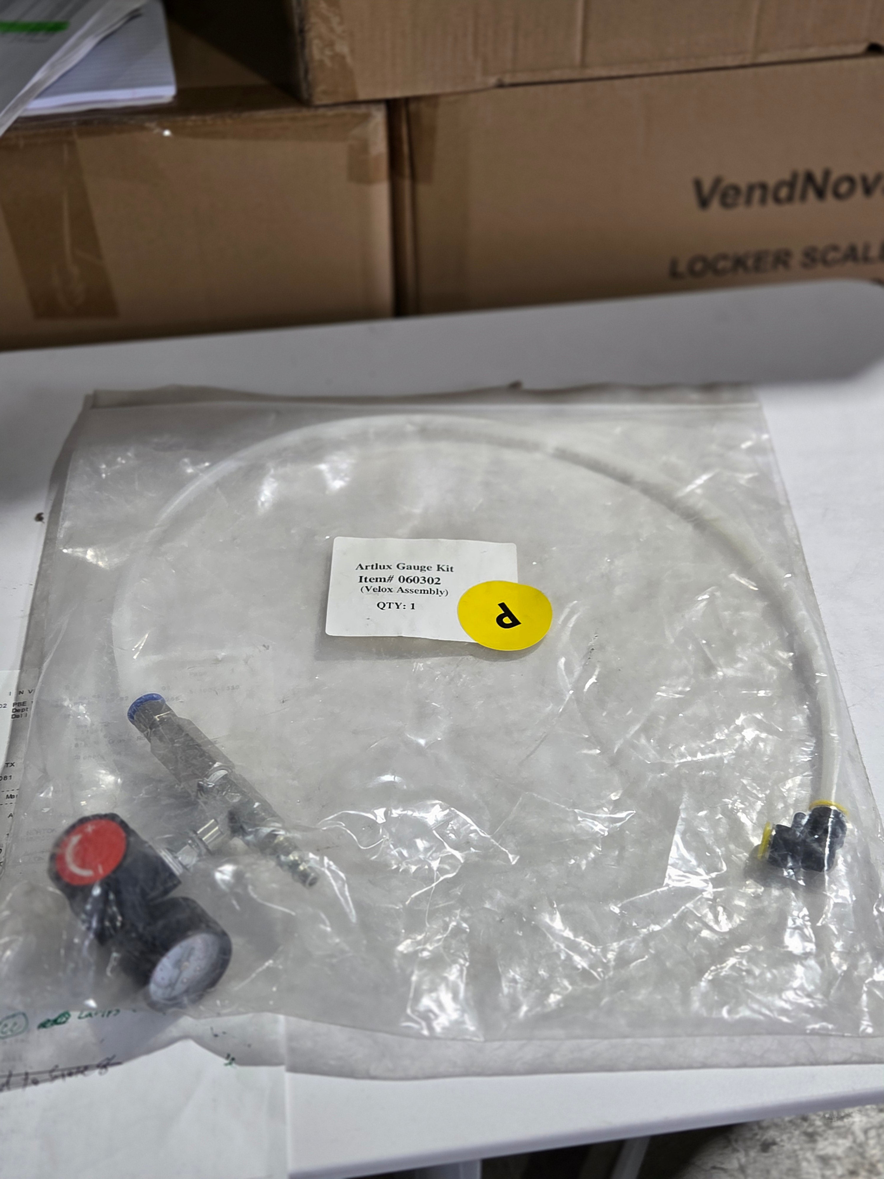 Medical device with tubing and connectors on a white surface, surrounded by cardboard boxes.