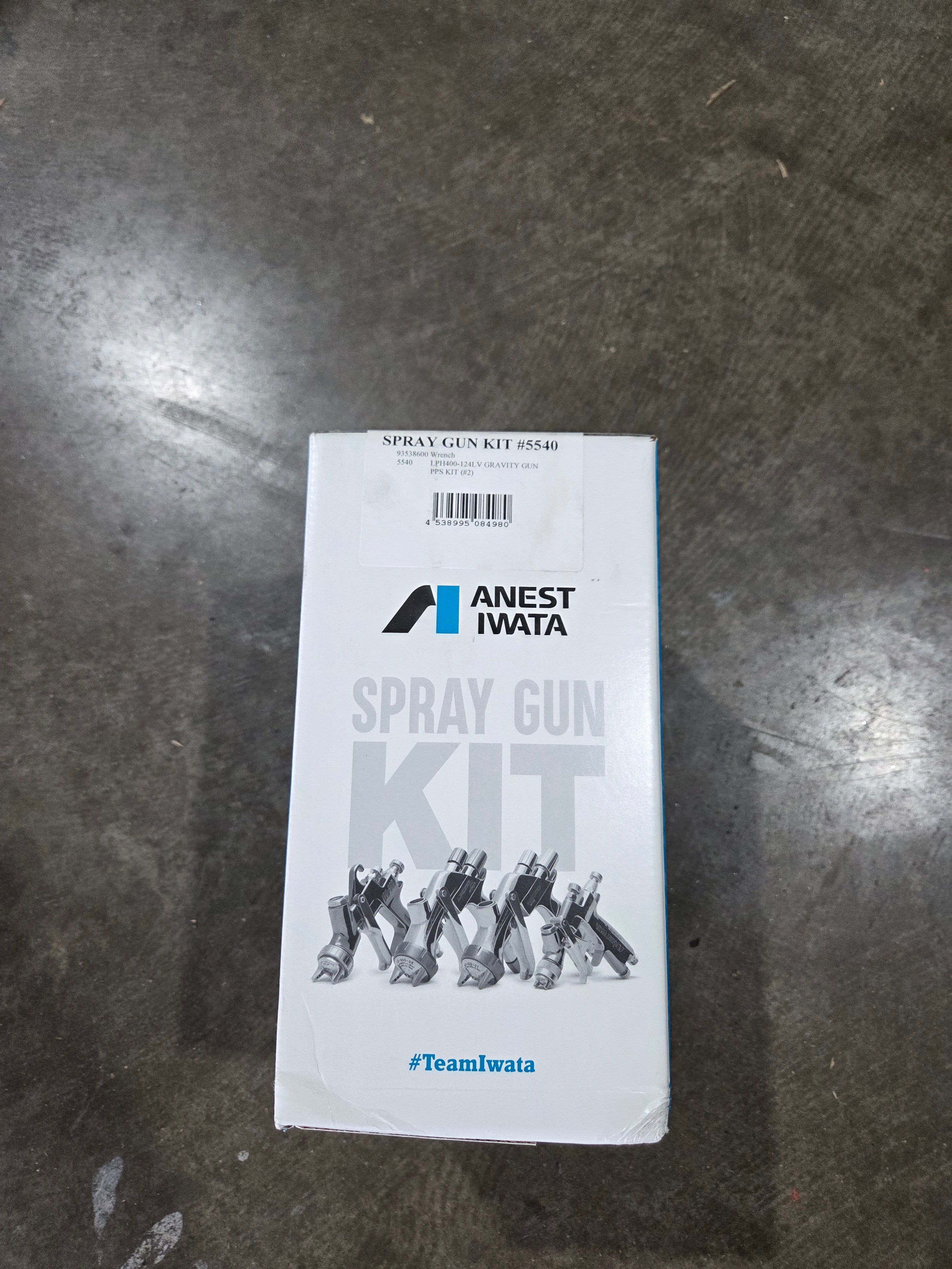 Amest Iwata spray gun kit packaging on a metallic surface