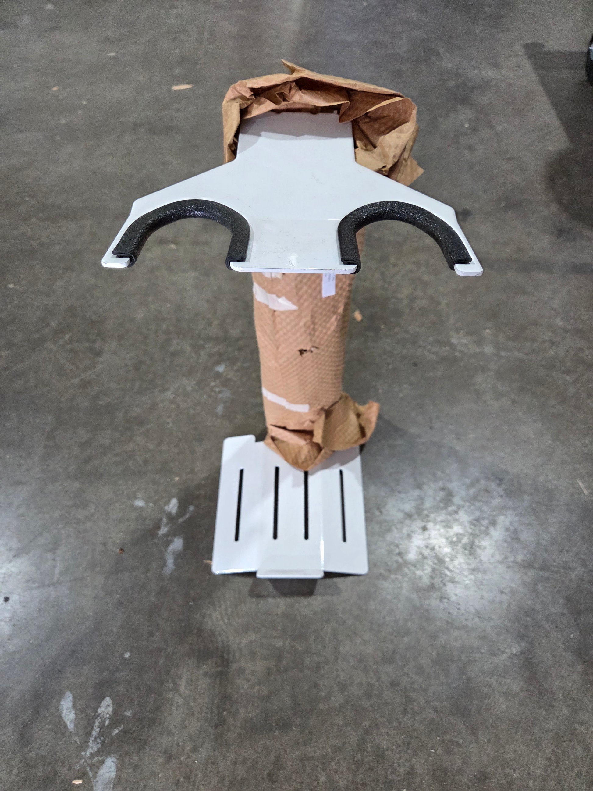 White and black object resembling a weapon or tool on a gray concrete floor