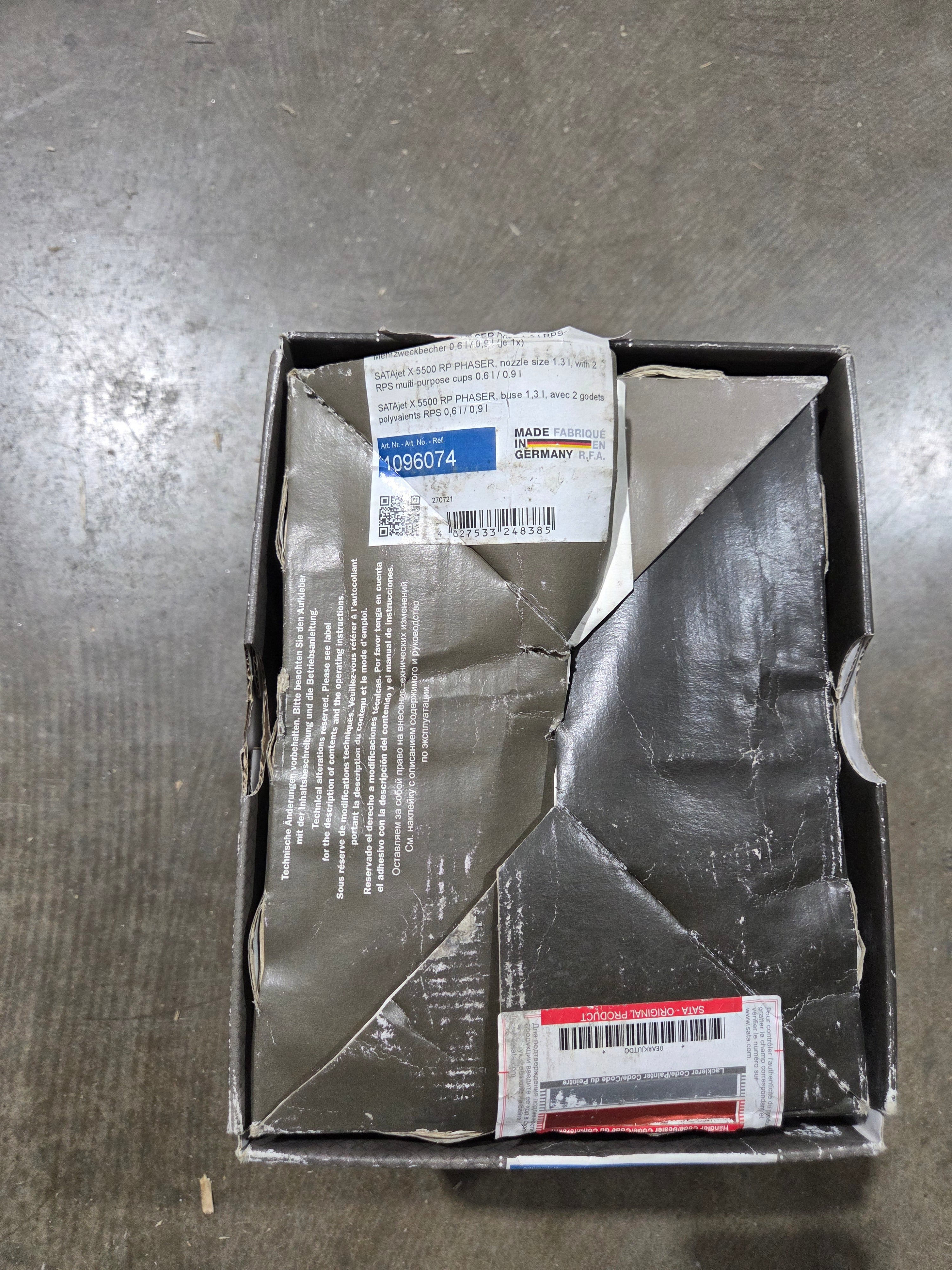 Damaged cardboard box with torn sides on a gray surface