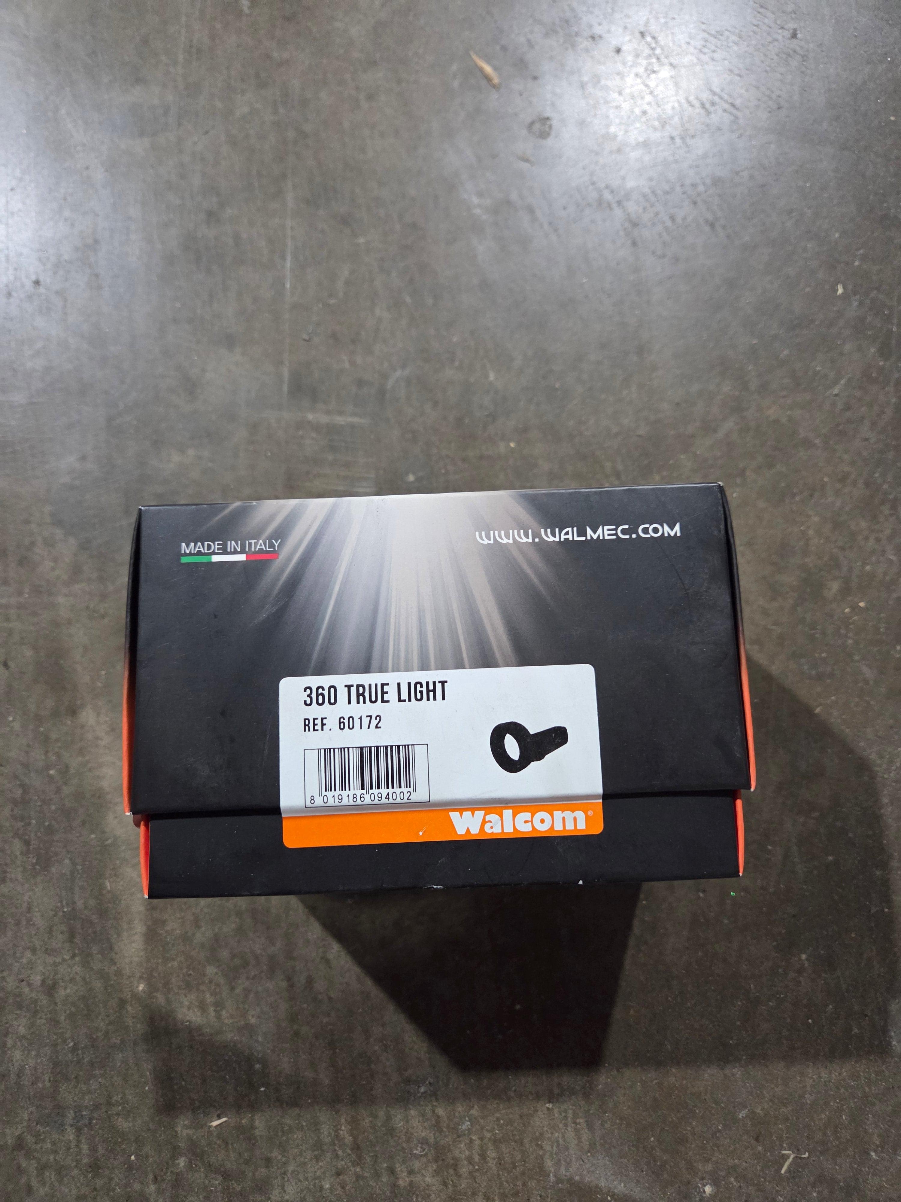Black and orange packaging box with Walcom branding on a dark surface