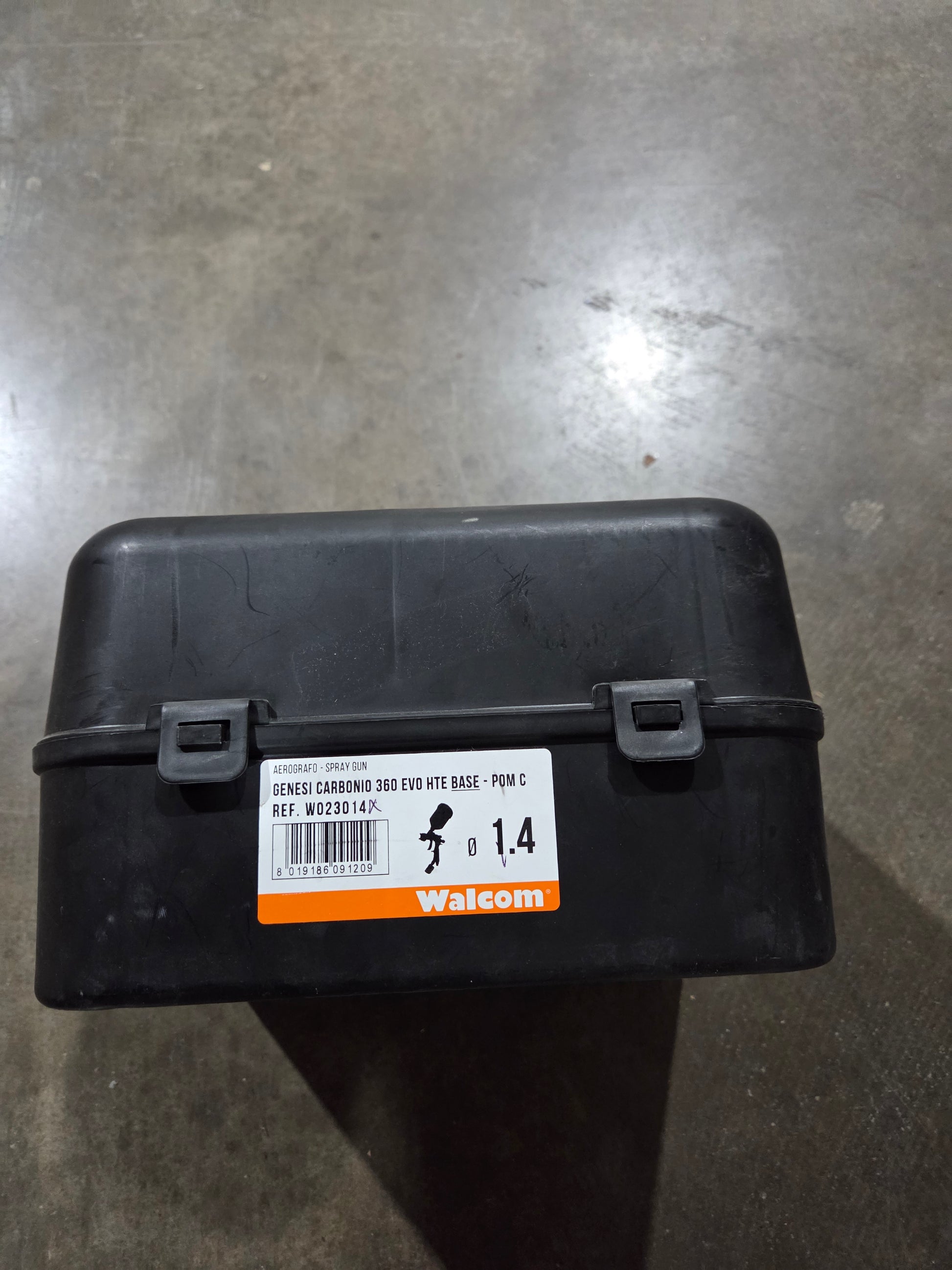 Black plastic container with a label on a gray surface