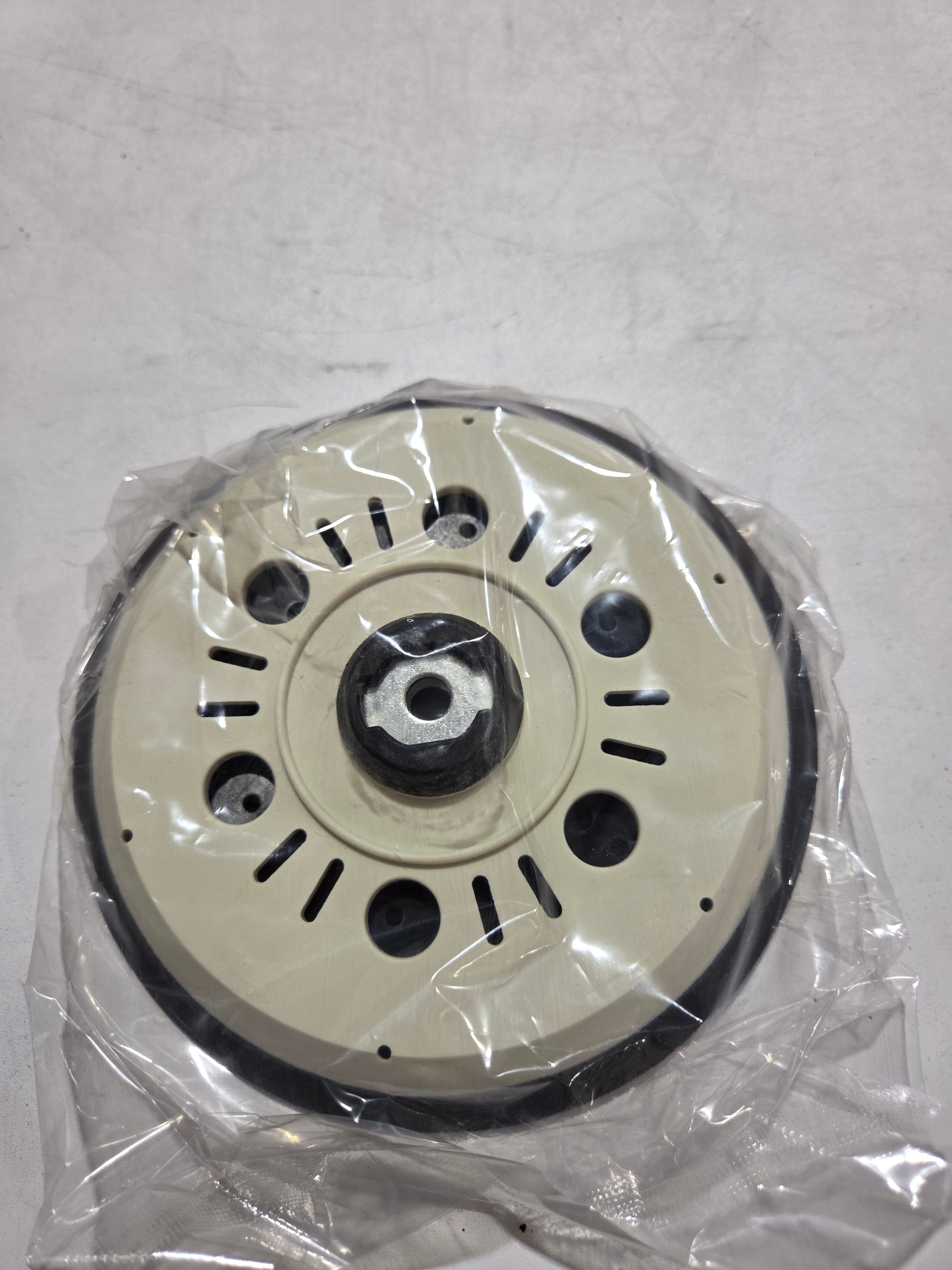 Mechanical component wrapped in clear plastic on a light gray background