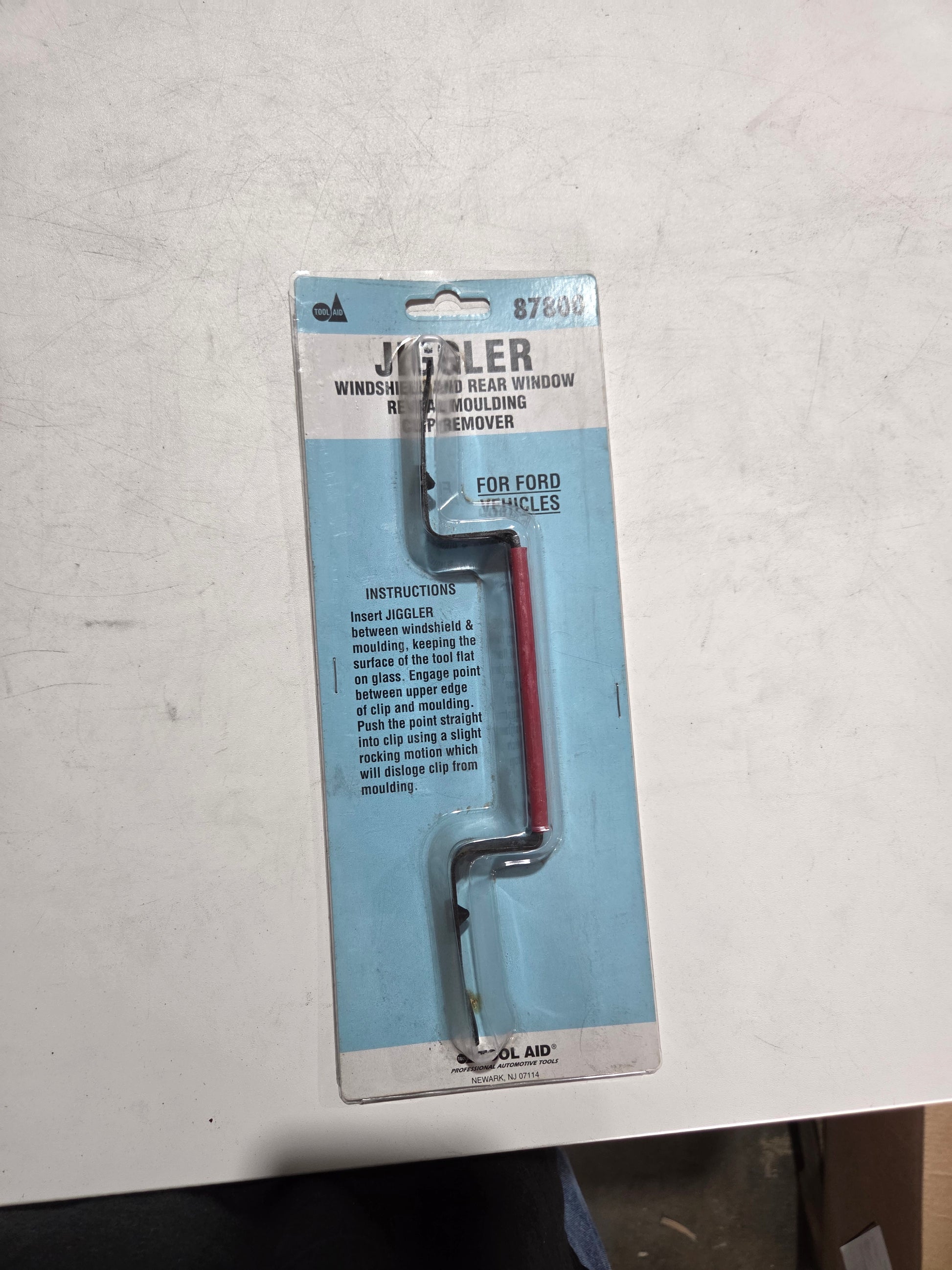 Jeweler's wire cutters on a blue packaging card with text, placed on a white surface.