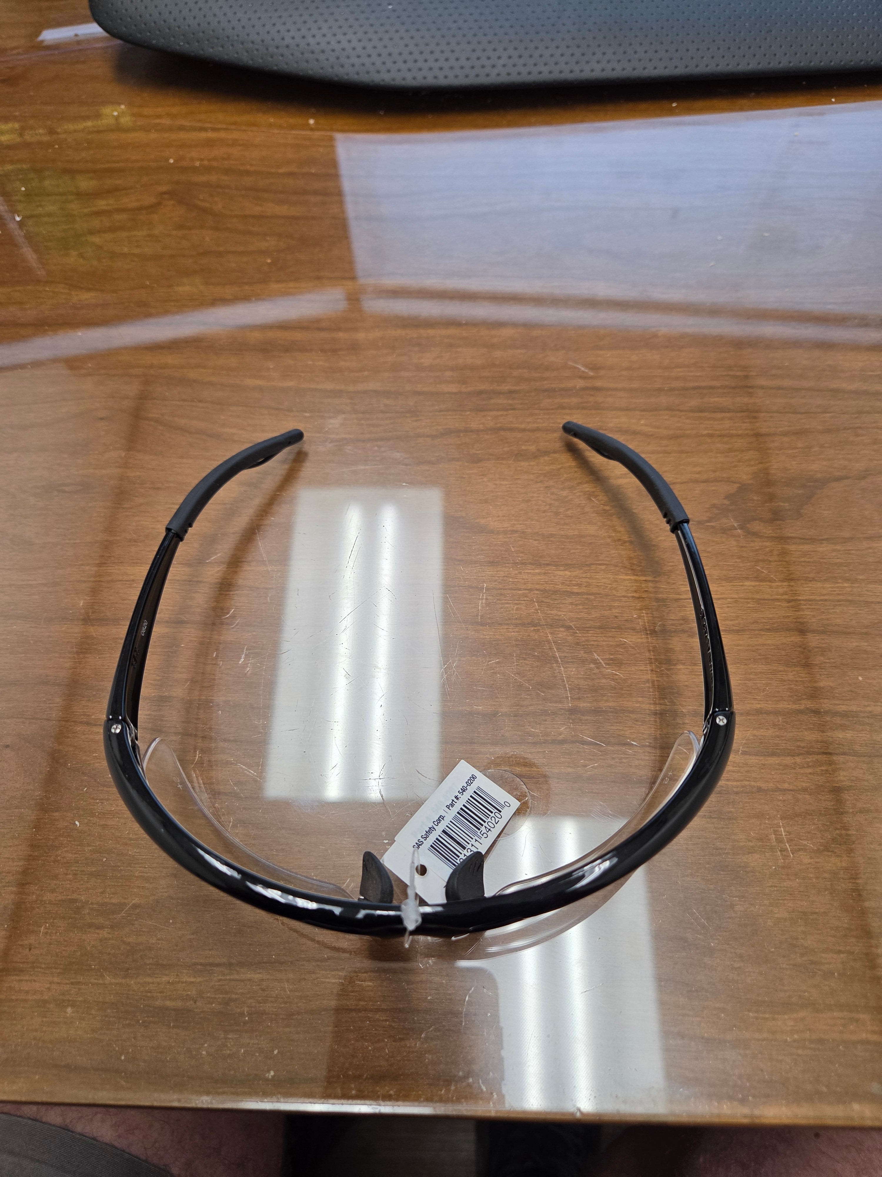 Black-framed glasses with a tag on a wooden surface